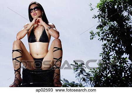 Stock Image - Woman in bikini, resting head on hands, legs apart . Fotosearch