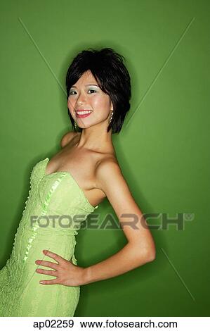 Stock Photo - Woman in green dress, hands on hip, smiling at camera . Fotosearch