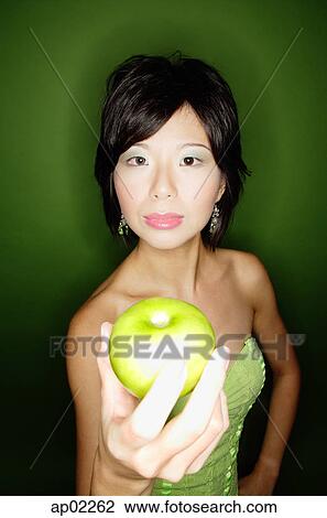 Woman in green dress, holding green apple towards camera View Large Photo Image Stock Image - Woman in green dress, holding green apple towards camera. Fotosearch