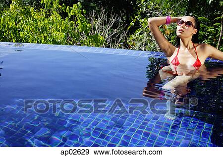 Woman in red bikini, sitting in swimming pool, hand on head View Large Photo Image Stock Photo - Woman in red bikini, sitting in swimming pool, hand on head. Fotosearch