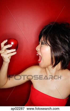Woman in red tube tope holding red apple, mouth open View Large Photo Image Stock Photo - Woman in red tube tope holding red apple, mouth open . Fotosearch