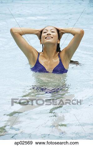 Stock Photo - Woman in swimming pool, hands on head . Fotosearch