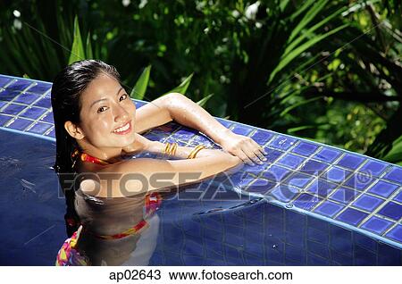 Woman leaning on edge of swimming pool, smiling at camera View Large Photo Image Stock Image - Woman leaning on edge of swimming pool, smiling at camera. Fotosearch