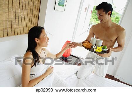 Woman lying in bed, man holding breakfast tray, holding womans hand View Large Photo Image Stock Image - Woman lying in bed, man holding breakfast tray, holding womans hand . Fotosearch