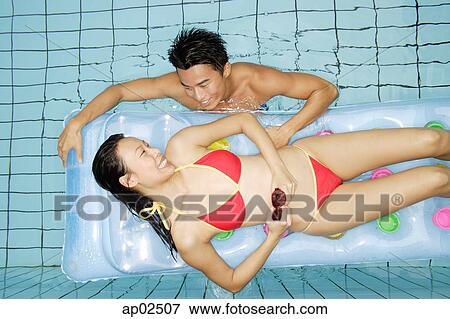 Woman lying on pool raft, man in water next to her View Large Photo Image Stock Photo - Woman lying on pool raft, man in water next to her . Fotosearch