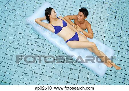 Woman lying on pool raft, smiling at man in water next to her View Large Photo Image Stock Image - Woman lying on pool raft, smiling at man in water next to her. Fotosearch