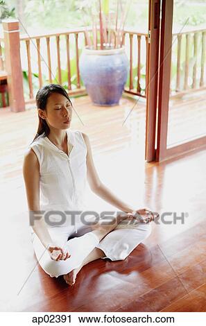 Stock Image - Woman practicing yoga, sitting in lotus position . Fotosearch