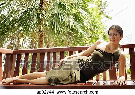 Woman reclining on wooden bench View Large Photo Image Picture - Woman reclining on wooden bench . Fotosearch