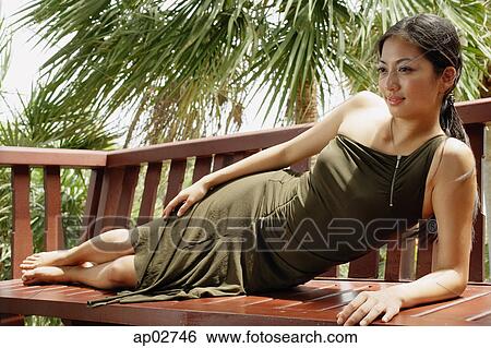 Woman reclining on wooden bench View Large Photo Image Stock Photograph - Woman reclining on wooden bench . Fotosearch