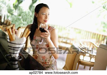 Woman sitting at bar counter, drinking wine, looking away View Large Photo Image Picture - Woman sitting at bar counter, drinking wine, looking away . Fotosearch