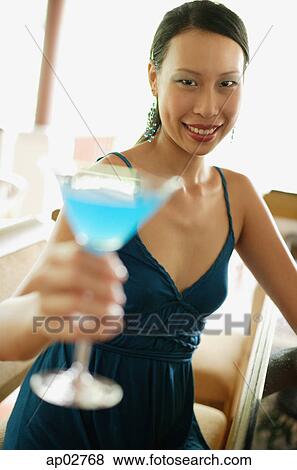 Woman sitting at bar counter, holding cocktail, smiling View Large Photo Image Stock Photo - Woman sitting at bar counter, holding cocktail, smiling . Fotosearch