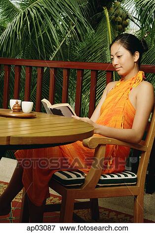Woman sitting at table, reading a book View Large Photo Image Stock Photo - Woman sitting at table, reading a book . Fotosearch