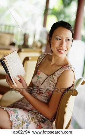 Picture - Woman sitting, holding a book, looking over shoulder . Fotosearch