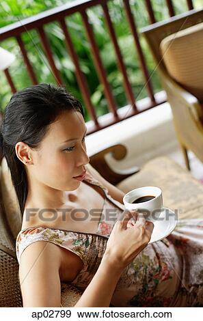 Woman sitting, holding cup and saucer View Large Photo Image Stock Photo - Woman sitting, holding cup and saucer . Fotosearch