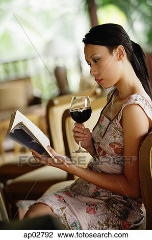 Woman sitting, holding wine glass, reading a book View Large Photo Image Stock Image - Woman sitting, holding wine glass, reading a book . Fotosearch