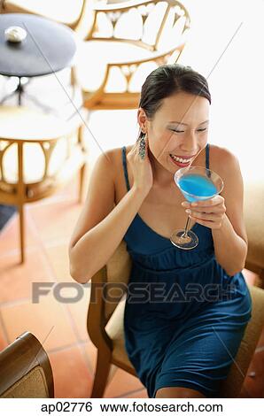 Woman sitting on chair, drinking cocktail, high angle view View Large Photo Image Stock Photograph - Woman sitting on chair, drinking cocktail, high angle view . Fotosearch