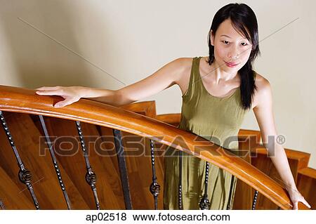 Woman standing on staircase, hands on banister View Large Photo Image Stock Photo - Woman standing on staircase, hands on banister. Fotosearch