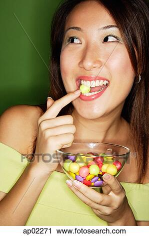 Woman with bowl of candy, putting candy into mouth View Large Photo Image Stock Image - Woman with bowl of candy, putting candy into mouth . Fotosearch