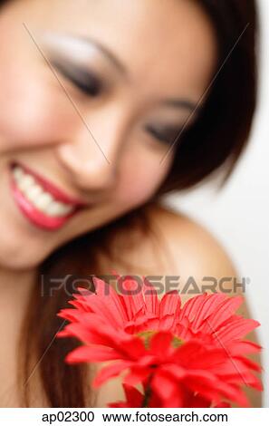 Stock Image - Woman with flower, focus on the foreground . Fotosearch