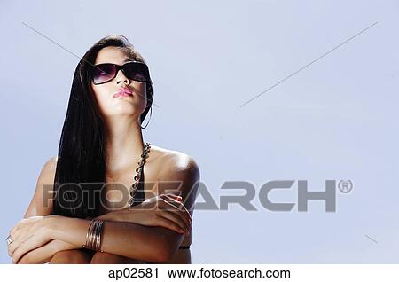 Stock Image - Woman with sunglasses, arms crossed, looking away. Fotosearch