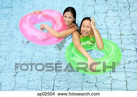 Picture - Women in swimming pool, holding inflatable ring, looking at camera . Fotosearch