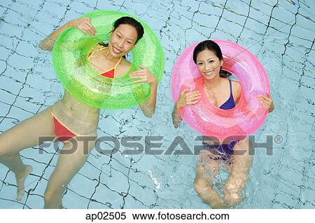 Women in swimming pool, using inflatable rings, looking at camera View Large Photo Image Stock Photography - Women in swimming pool, using inflatable rings, looking at camera . Fotosearch