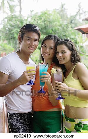 Stock Photo - Young adults holding cocktails, looking at camera . Fotosearch