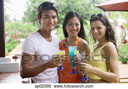 Stock Photography - Young adults holding drinks looking at camera . Fotosearch