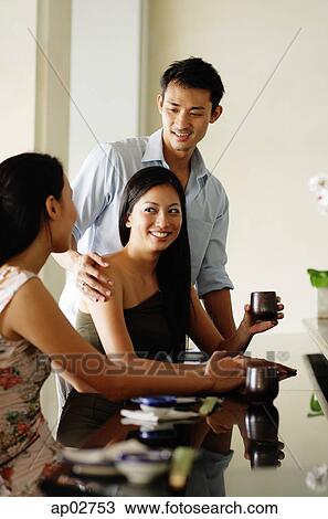 Young adults in restaurant, women sitting, man standing next to woman View Large Photo Image Stock Image - Young adults in restaurant, women sitting, man standing next to woman . Fotosearch