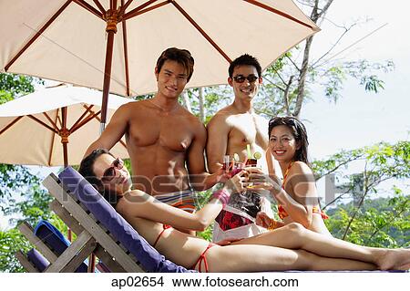 Young adults in swimwear, toasting with drinks View Large Photo Image Picture - Young adults in swimwear, toasting with drinks. Fotosearch