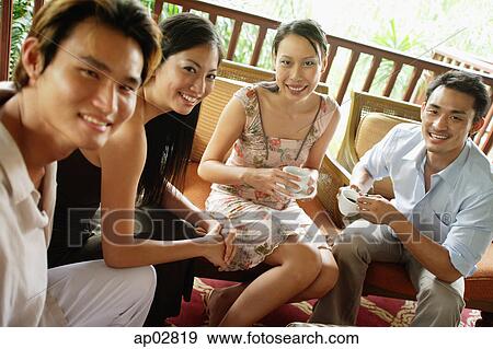 Young adults sitting, having coffee, looking at camera View Large Photo Image Stock Photo - Young adults sitting, having coffee, looking at camera . Fotosearch