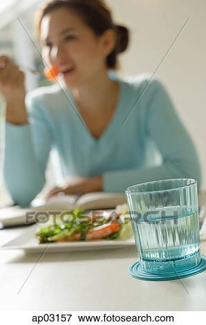 Young woman eating salad, focus on the foreground View Large Photo Image Stock Photo - Young woman eating salad, focus on the foreground . Fotosearch