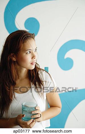 Young woman looking away, holding glass View Large Photo Image Stock Photo - Young woman looking away, holding glass. Fotosearch