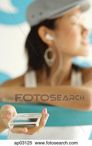 Young woman looking away, listening to MP3 player View Large Photo Image Stock Photography - Young woman looking away, listening to MP3 player . Fotosearch