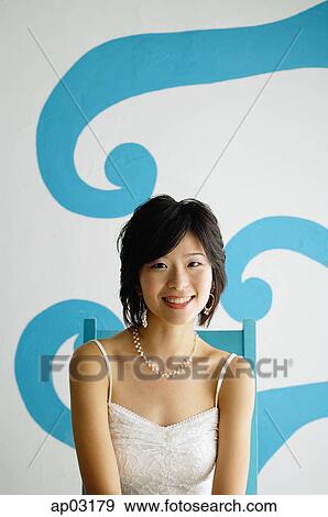 Young woman sitting on chair, looking at camera View Large Photo Image Stock Photo - Young woman sitting on chair, looking at camera. Fotosearch