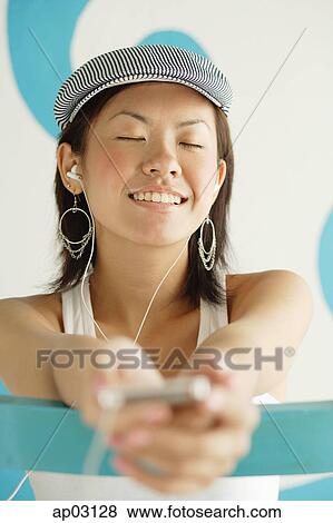 Stock Photo - Young woman wearing beret, listening to MP3 player, eyes closed . Fotosearch