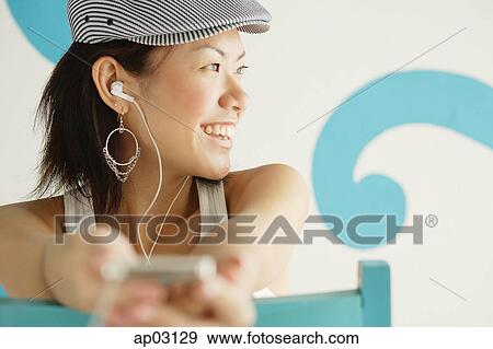 Young woman wearing beret, listening to MP3 player, looking away, smiling View Large Photo Image Stock Photo - Young woman wearing beret, listening to MP3 player, looking away, smiling . Fotosearch