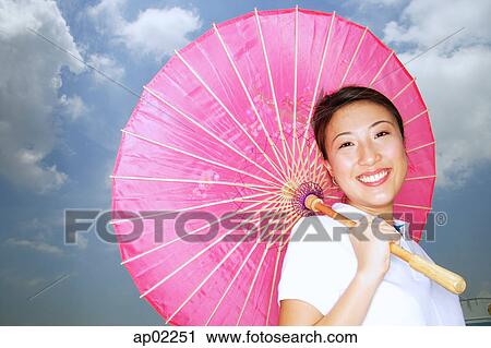 Young woman with pink umbrella, smiling at camera View Large Photo Image Stock Image - Young woman with pink umbrella, smiling at camera . Fotosearch