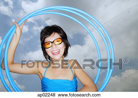 Stock Photo - Young woman with sunglasses, holding hoola hoops . Fotosearch