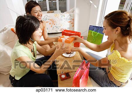 Young women at home, celebrating birthday, passing gift View Large Photo Image Stock Image - Young women at home, celebrating birthday, passing gift . Fotosearch
