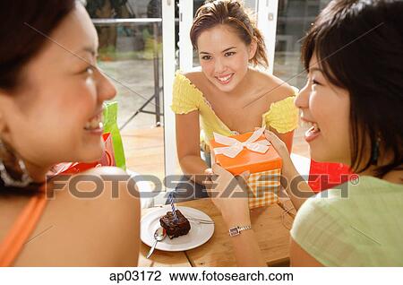 Young women at home, one holding gift View Large Photo Image Stock Image - Young women at home, one holding gift . Fotosearch