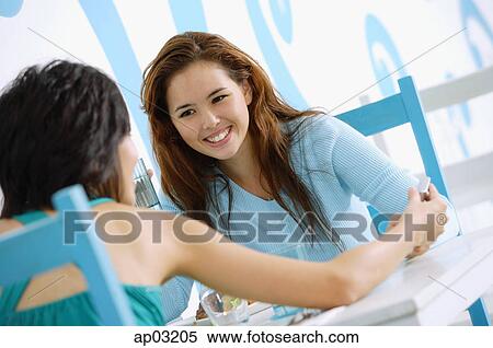 Young women in cafe, looking at mobile phone View Large Photo Image Stock Photography - Young women in cafe, looking at mobile phone. Fotosearch