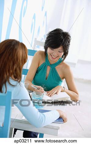 Young women in cafe, one writing in notebook, over the shoulder view View Large Photo Image Stock Image - Young women in cafe, one writing in notebook, over the shoulder view . Fotosearch