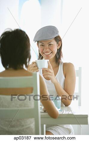 Young women in cafe, sitting face to face, having coffee View Large Photo Image Stock Photo - Young women in cafe, sitting face to face, having coffee . Fotosearch