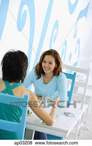 Stock Photo - Young women in cafe, sitting face to face . Fotosearch