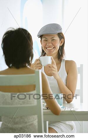 Young women in cafe, sitting face to face View Large Photo Image Stock Photograph - Young women in cafe, sitting face to face . Fotosearch