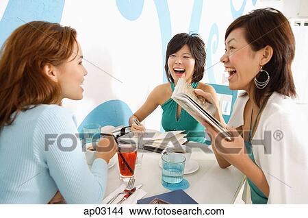 Young women in cafe, talking over drinks View Large Photo Image Picture - Young women in cafe, talking over drinks. Fotosearch