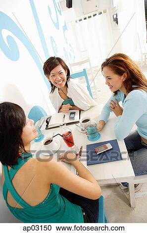 Stock Image - Young women sitting in cafe. Fotosearch