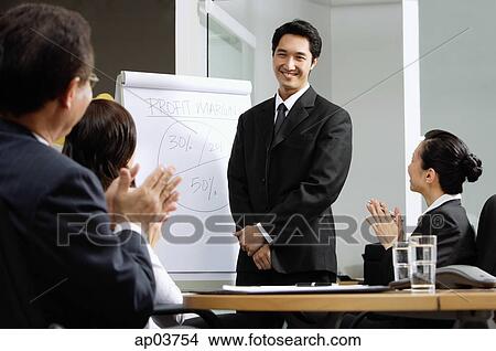 Stock Photo - Businessman standing next to flipchart, other executives clapping. Fotosearch - Search Stock Images, Mural Photographs, Pictures, and Clipart Photos
