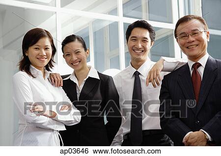 Stock Photograph - Business people standing side by side, smiling at camera . Fotosearch